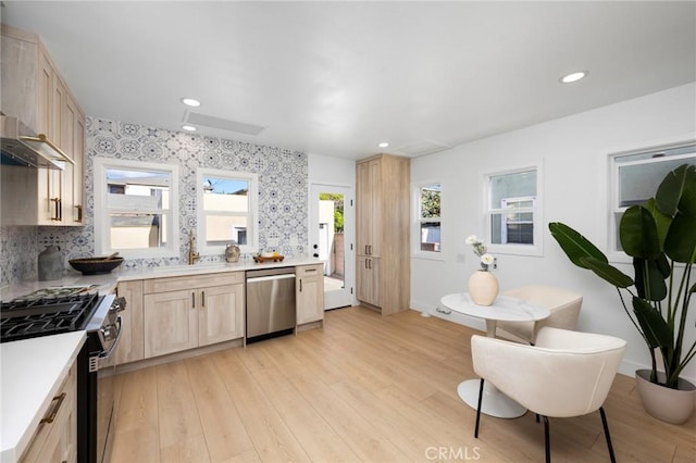 kitchen featuring stainless steel appliances, light wood-style flooring, a sink, and light brown cabinetry
