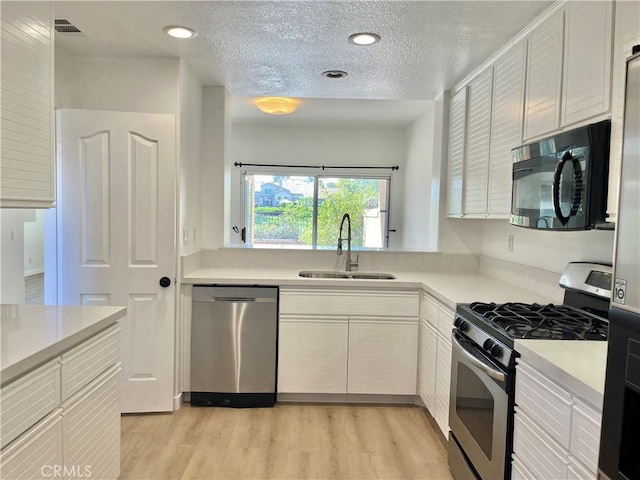 kitchen with light countertops, visible vents, stainless steel appliances, light wood finished floors, and a sink