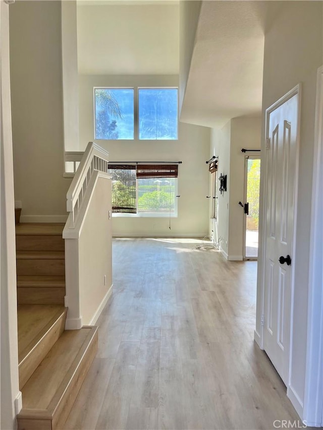 entryway featuring baseboards, stairway, and light wood-style floors