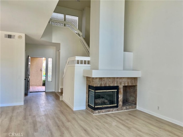 unfurnished living room with wood finished floors, visible vents, a fireplace, and baseboards