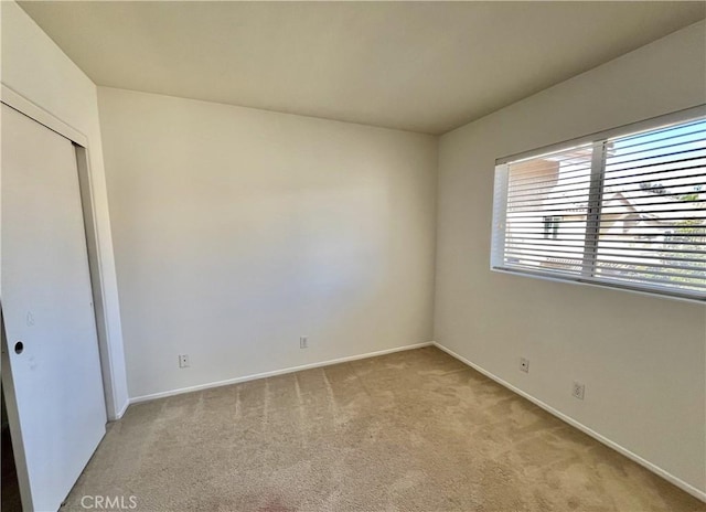 unfurnished room with baseboards and light colored carpet