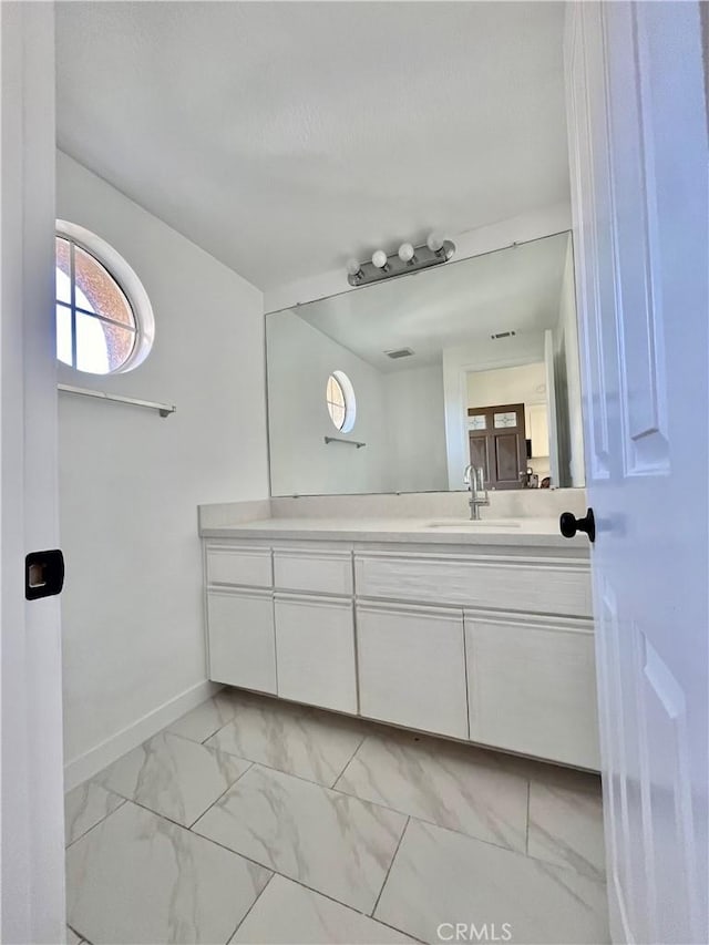 bathroom with vanity, marble finish floor, and baseboards