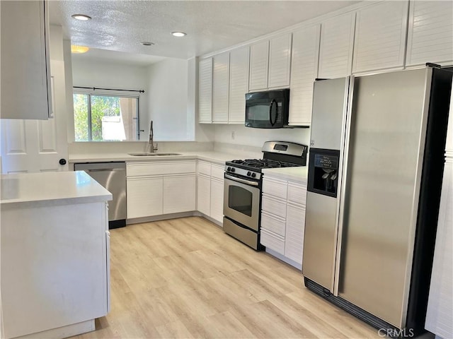 kitchen featuring recessed lighting, light countertops, light wood-style floors, stainless steel appliances, and a sink