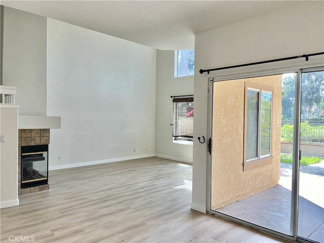 unfurnished living room featuring wood finished floors, baseboards, and a tile fireplace