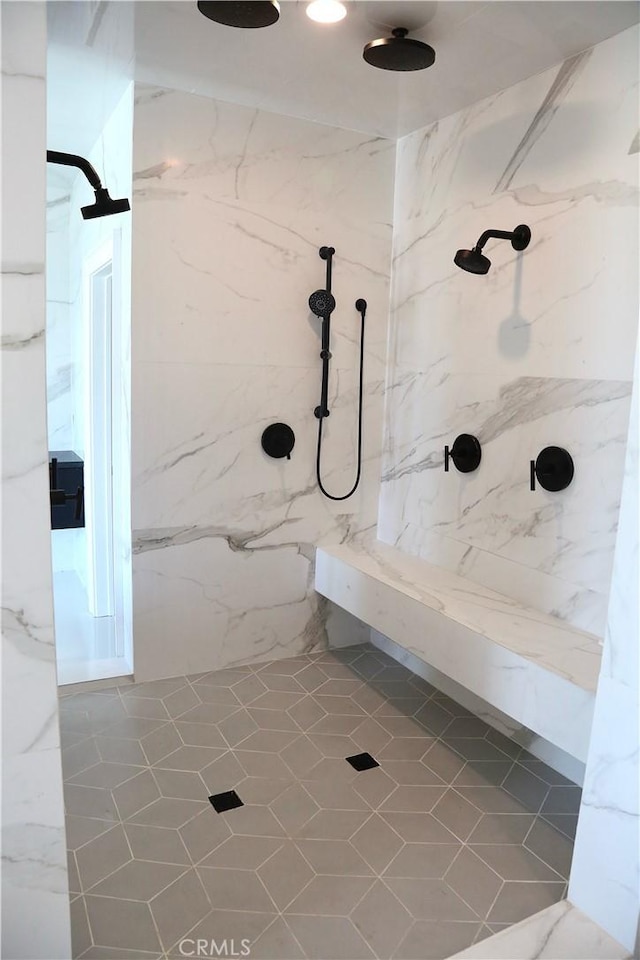 full bath with a marble finish shower and tile patterned flooring
