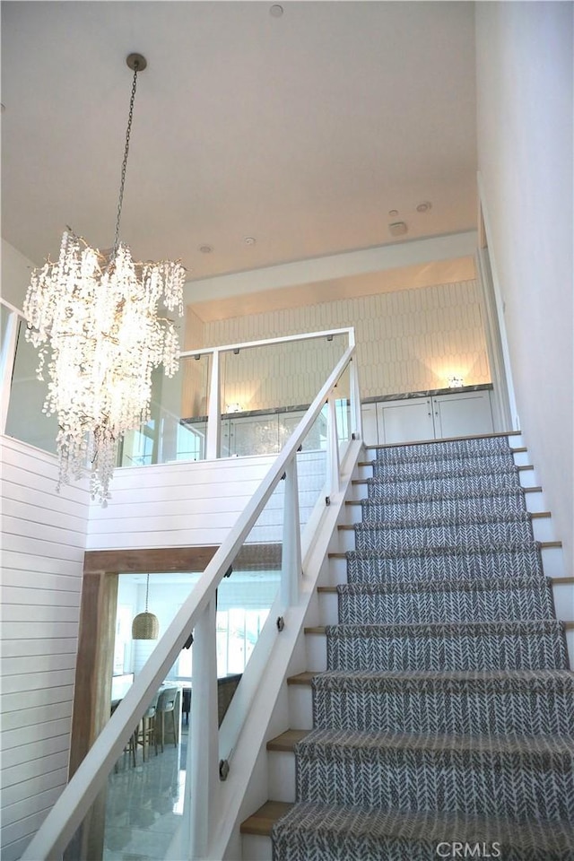 stairway featuring a healthy amount of sunlight and a notable chandelier