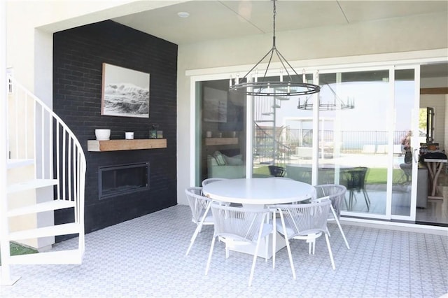 carpeted dining space featuring an outdoor fireplace, an inviting chandelier, and stairs
