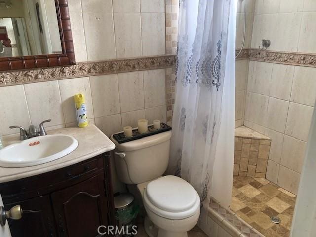 bathroom featuring tasteful backsplash, toilet, tile walls, a shower stall, and vanity