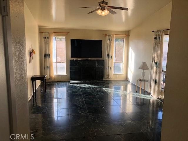 living room with baseboards, a ceiling fan, and a healthy amount of sunlight