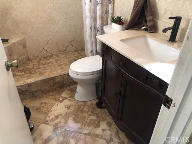 full bath with toilet, vanity, and a tile shower