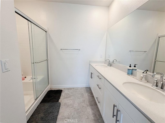 full bathroom with baseboards, a sink, double vanity, and a stall shower