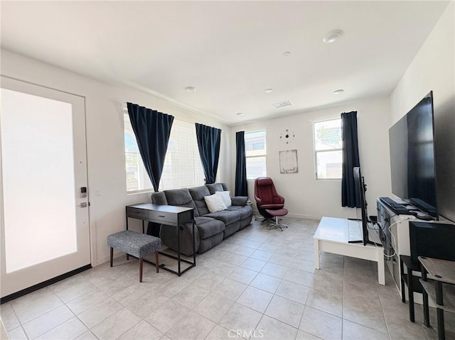 living area with baseboards, visible vents, and light tile patterned floors