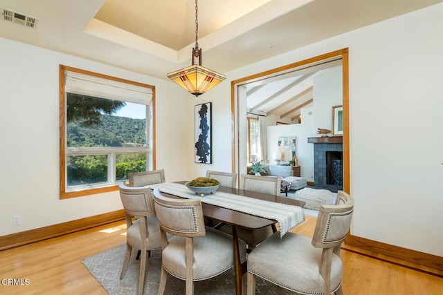 dining area with baseboards, light wood-type flooring, and a fireplace