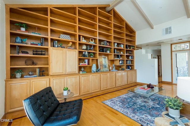 sitting room featuring beamed ceiling, light wood-style flooring, high vaulted ceiling, and built in features