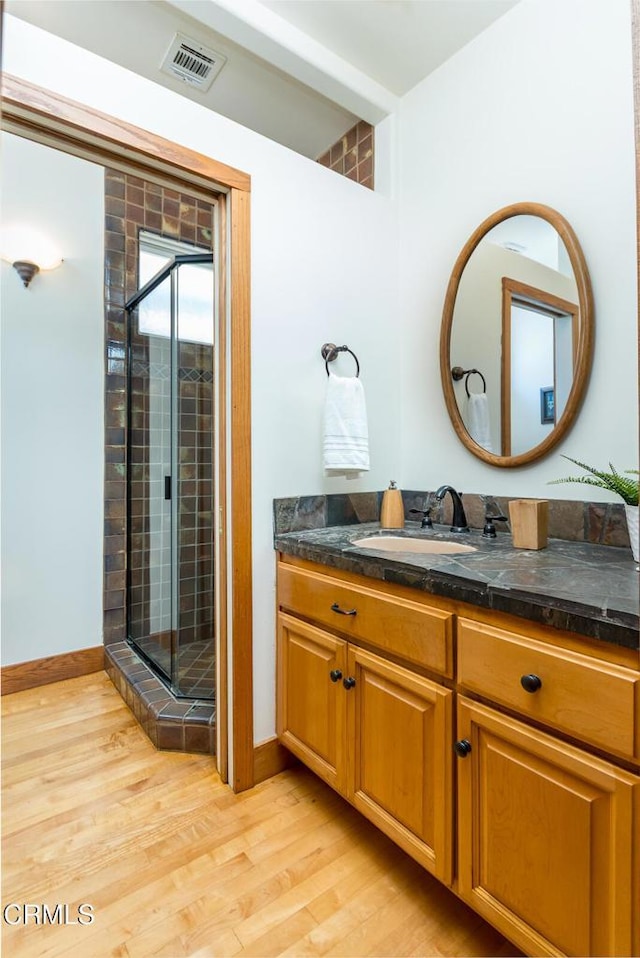 bathroom featuring wood finished floors, a shower stall, and vanity