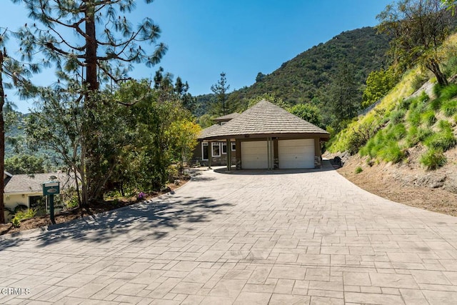 view of front of home featuring decorative driveway, an attached garage, and a mountain view