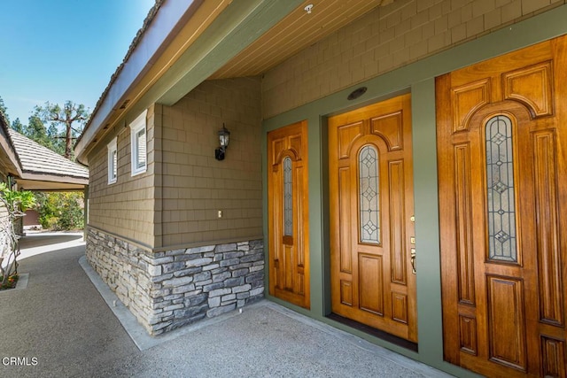 property entrance with stone siding and a porch