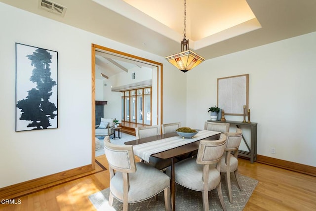dining area with light wood-style floors, baseboards, and vaulted ceiling