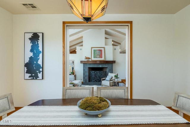 dining space featuring a tiled fireplace and lofted ceiling