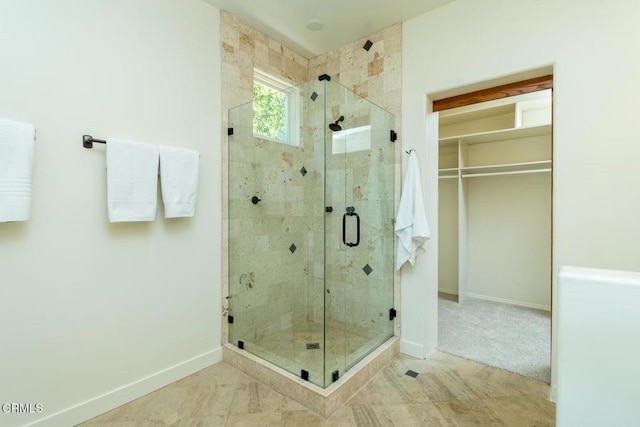 bathroom with baseboards, a stall shower, and a walk in closet