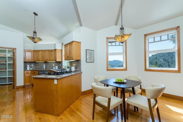 kitchen featuring vaulted ceiling, light wood-type flooring, backsplash, and decorative light fixtures