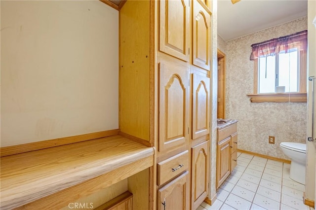 bathroom with baseboards, wallpapered walls, and toilet