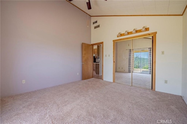 unfurnished room with visible vents, ceiling fan, carpet flooring, and lofted ceiling