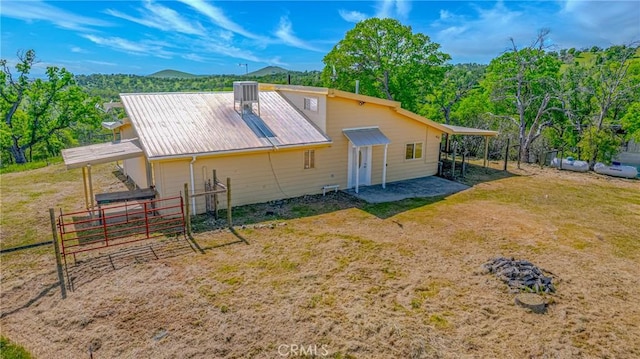 back of property with a mountain view, fence, metal roof, and central air condition unit