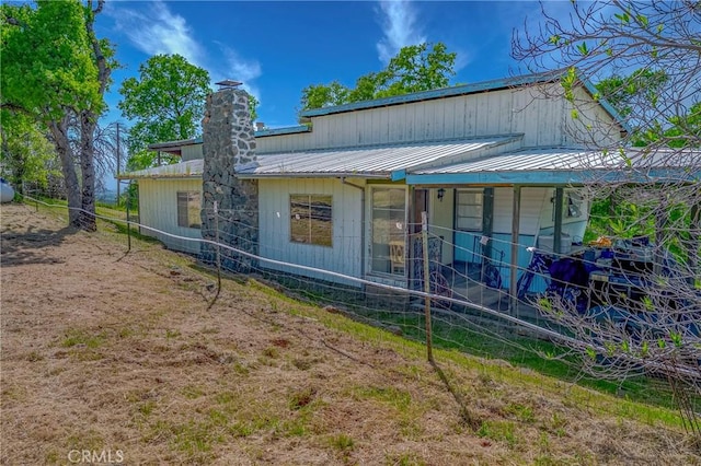 view of front of home featuring metal roof and a chimney