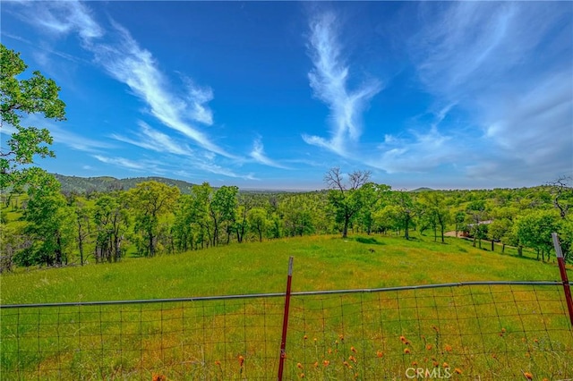 exterior space featuring a rural view, a forest view, and fence