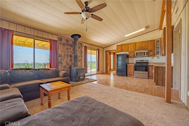 living room with a wood stove, a ceiling fan, and lofted ceiling