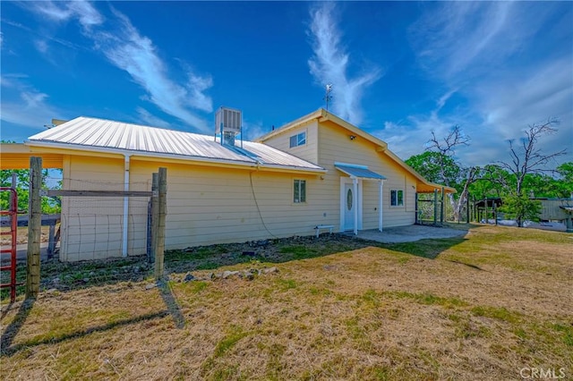 rear view of house with metal roof and a lawn