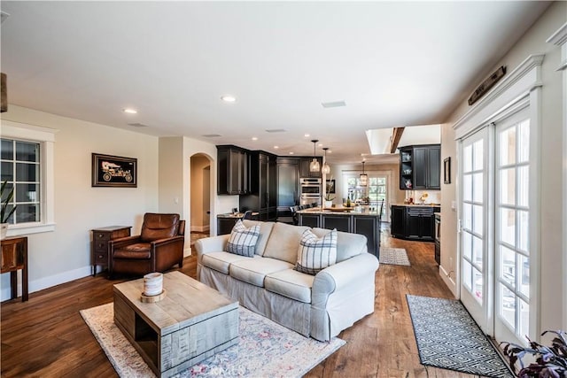 living area featuring recessed lighting, arched walkways, baseboards, and dark wood finished floors