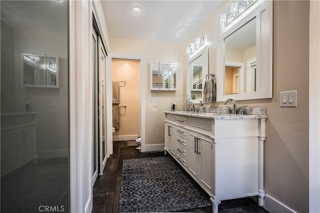 bathroom featuring a sink, baseboards, and double vanity