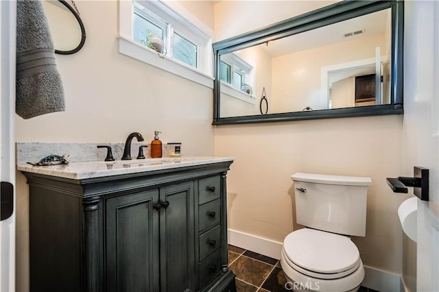 bathroom with toilet, visible vents, baseboards, and a sink