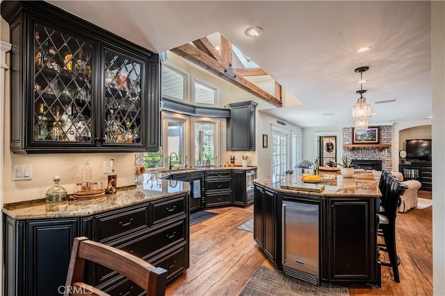 bar with recessed lighting, a fireplace, light wood-style flooring, pendant lighting, and bar