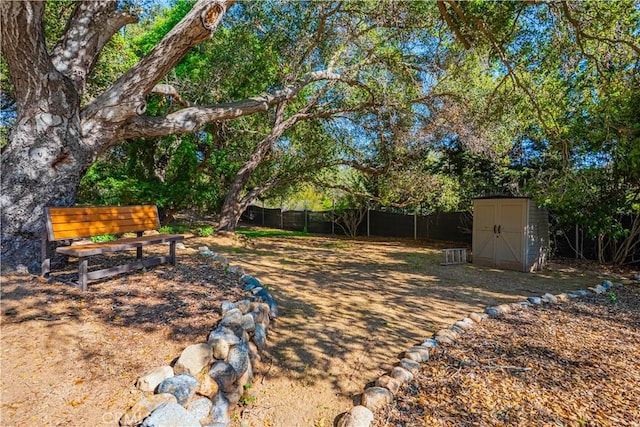view of yard featuring an outbuilding, fence, and a shed