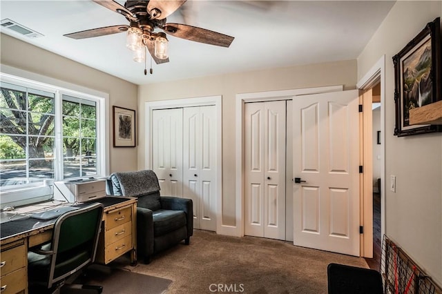 home office with dark carpet, ceiling fan, and visible vents