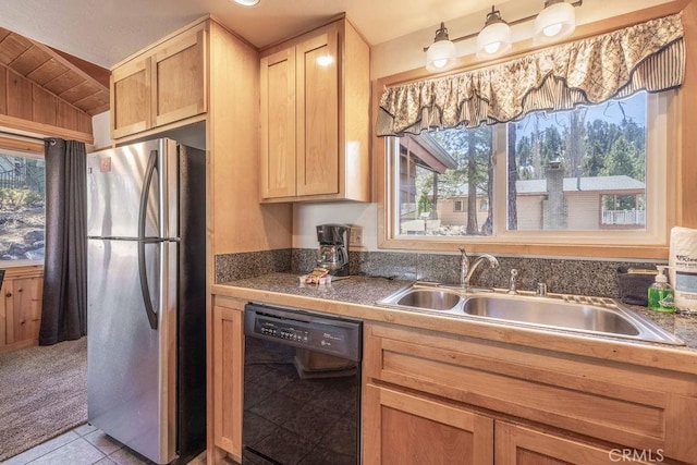 kitchen with black dishwasher, freestanding refrigerator, a sink, and plenty of natural light