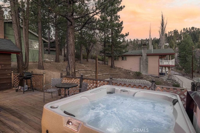 deck at dusk with grilling area and a hot tub