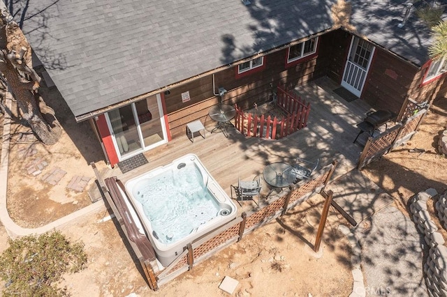 rear view of property with a deck, a hot tub, and a shingled roof