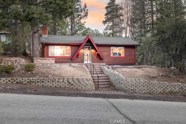 cabin featuring a chimney and faux log siding