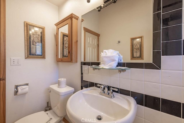 bathroom featuring a sink, toilet, and decorative backsplash