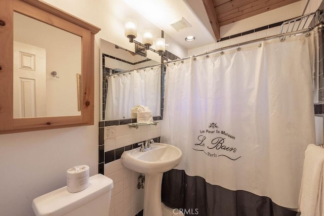 bathroom featuring visible vents, curtained shower, toilet, tile walls, and backsplash