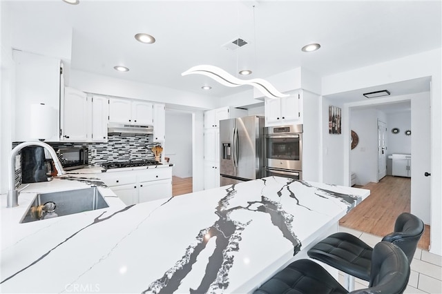 5201 Del Serra Cir, La Palma, CA 90623 - kitchen featuring stainless steel appliances, a sink, under cabinet range hood, light stone countertops, and decorative backsplash