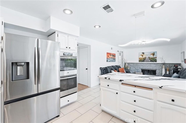 5201 Del Serra Cir, La Palma, CA 90623 - kitchen featuring stainless steel appliances, open floor plan, light tile patterned flooring, white cabinets, and a stone fireplace