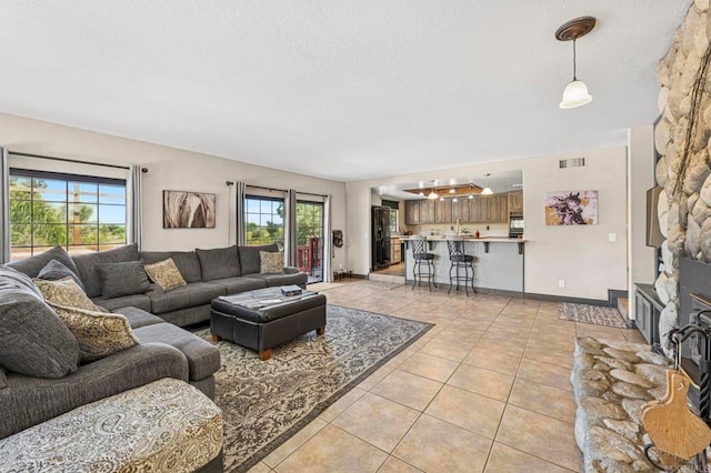 living area with a textured ceiling, light tile patterned flooring, and visible vents