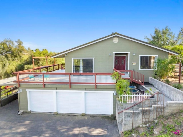 view of front of home featuring a deck, aphalt driveway, and a garage