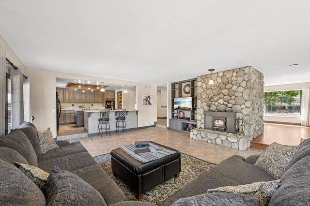 living room featuring a stone fireplace and light tile patterned flooring