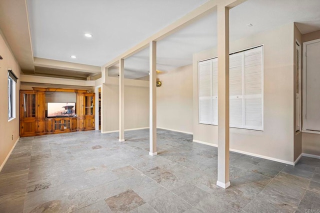 below grade area featuring baseboards, recessed lighting, and stone finish flooring